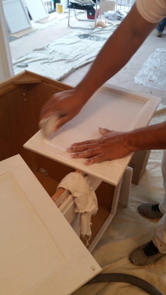 painter sanding kitchen cabinets that are to be painted
