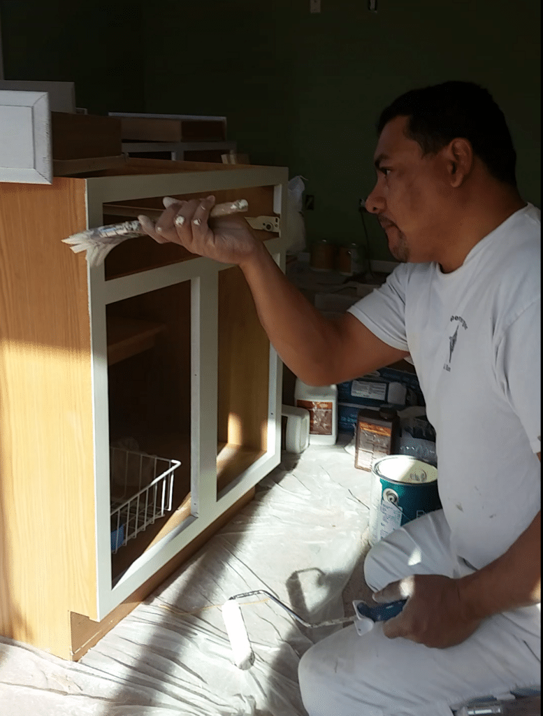 A painting company in Loudoun that has a painter, Roberto, painting a cabinet shell.
