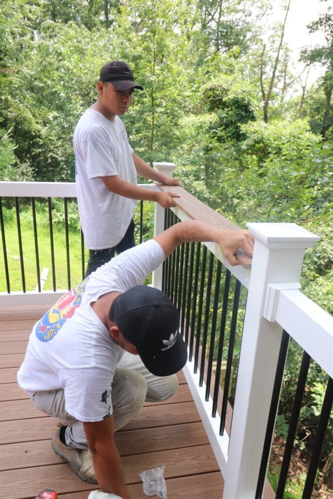 2 men repairing a deck railing