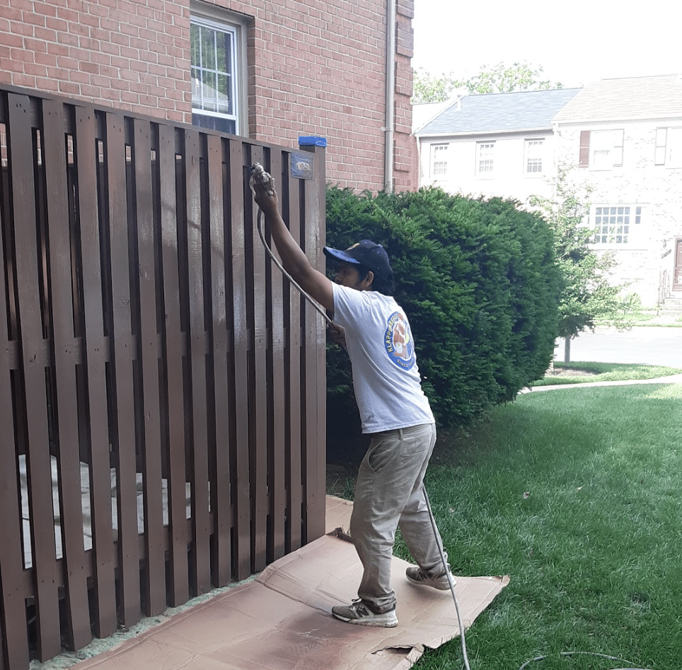 Painter for a day in Baltimore spraying a fence