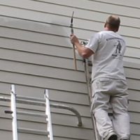 Washington DC Painter by Klappenberger & Son spraying siding on a ladder.