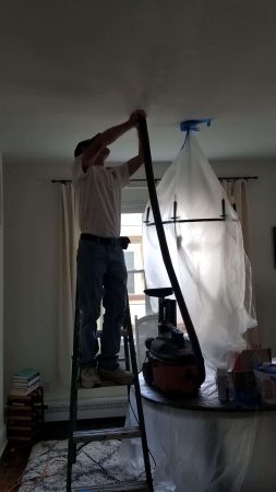 Interior painting contractor sand ceiling with a vacuum attachment