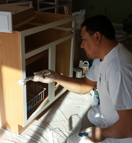 interior painting in Columbus shows Roberto brushing a kitchen cabinet with a fresh coat of paint.